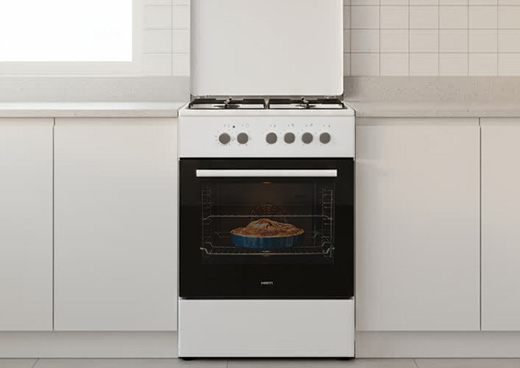 Kuchnia gazowo-elektryczna MPM-66-KGM-10 w zabudowie kuchennej. W piekarniku widoczne ciasto.